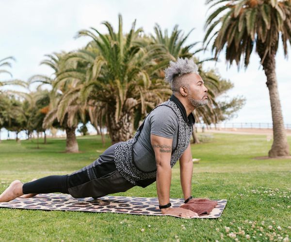 A man stretching peacefully in a park at sunrise, embodying a sense of calm and well-being.