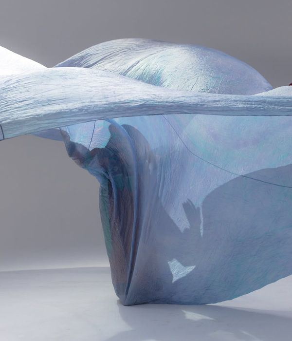 A woman in light blue sportswear performing a fluid cardio movement in a bright, clean studio.